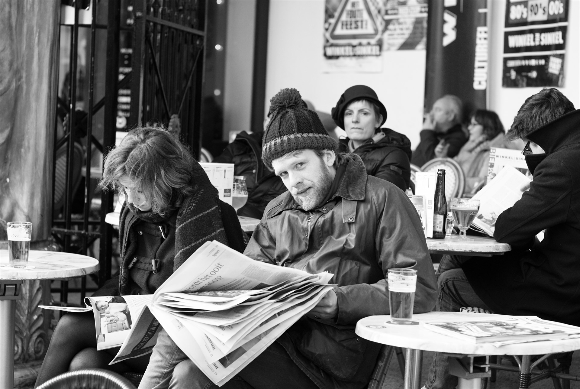 Man reading a newspaper at a café terrace.
