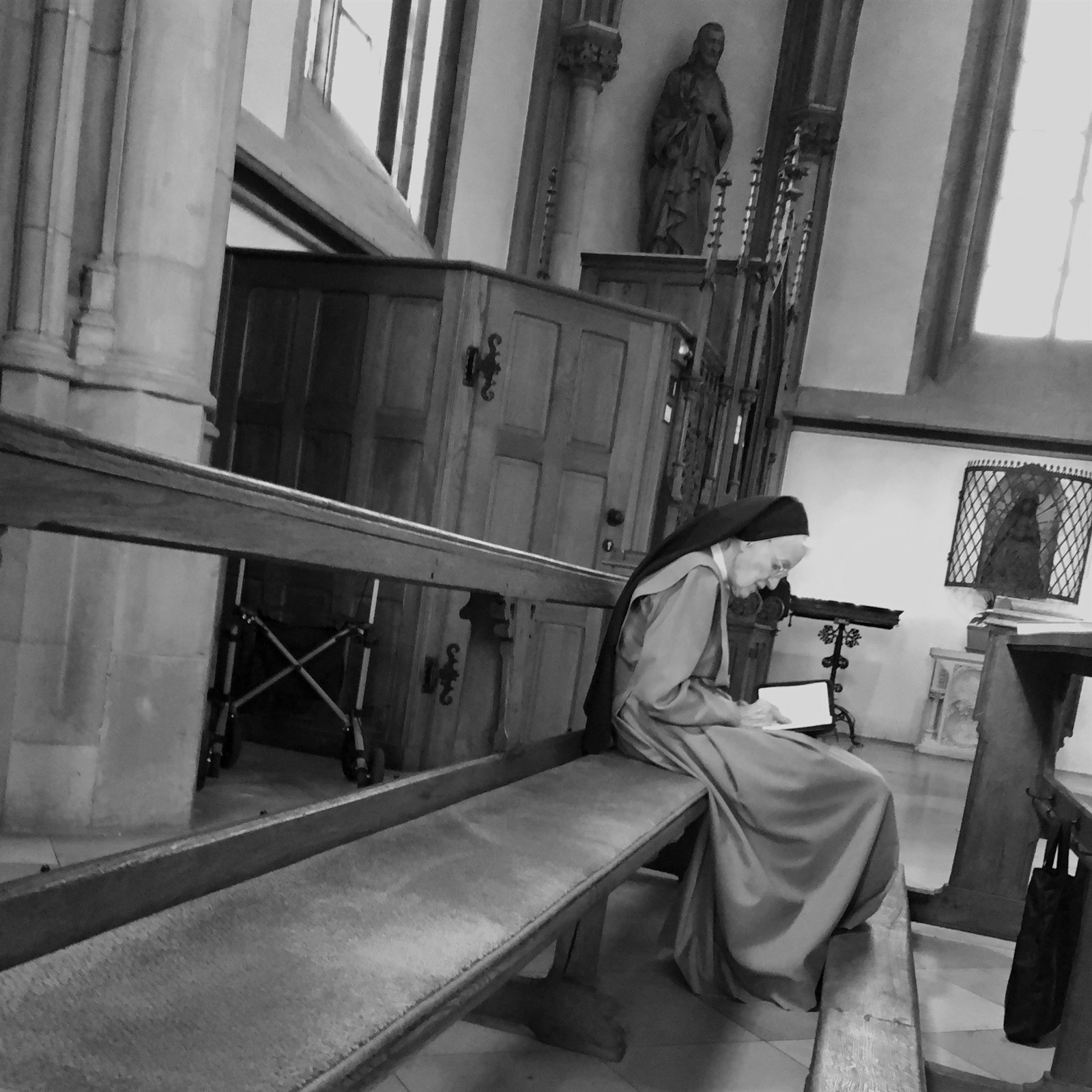 Woman in a religious habit seated alone inside a church.