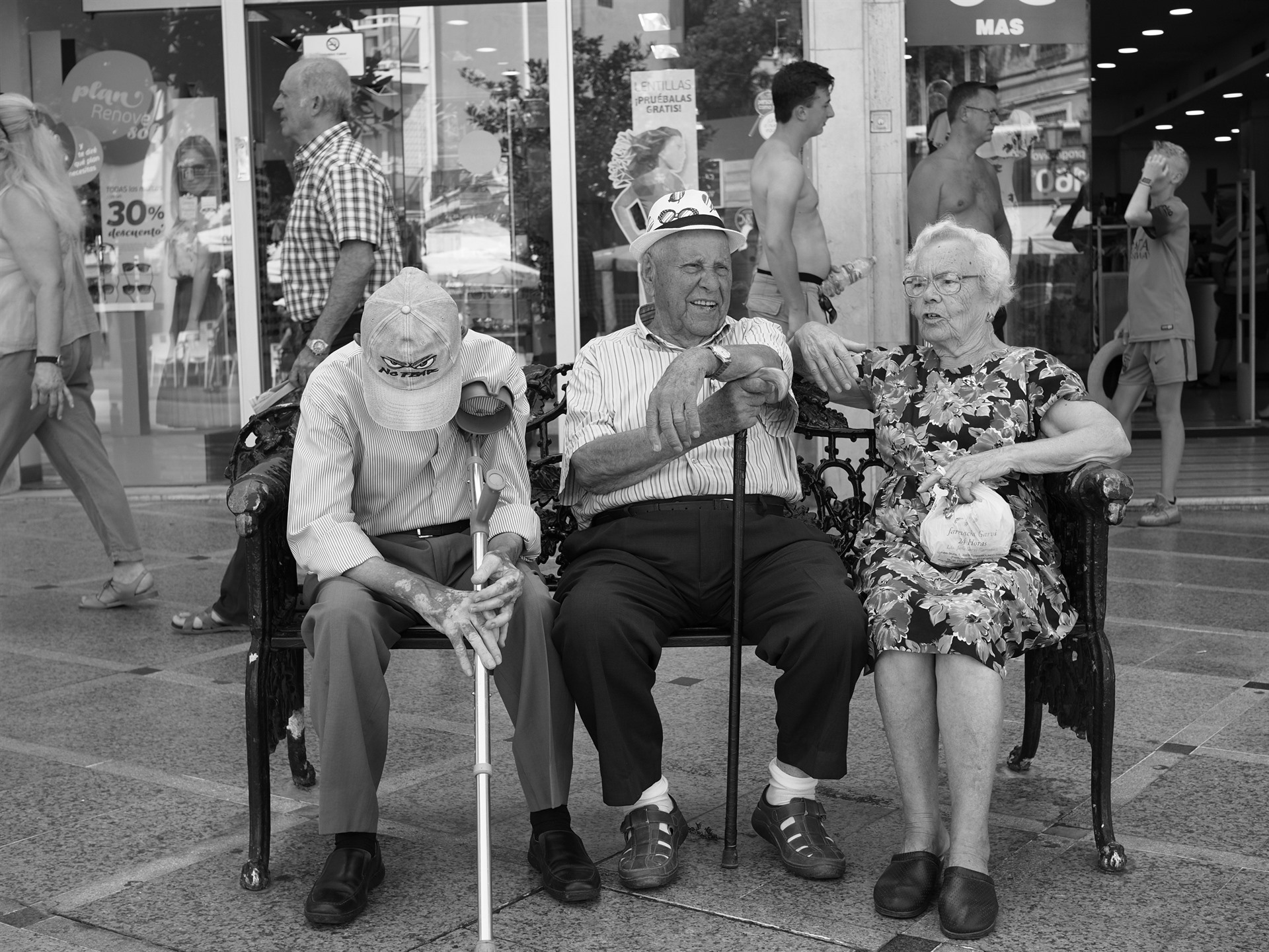 Three older people sitting on a bench.