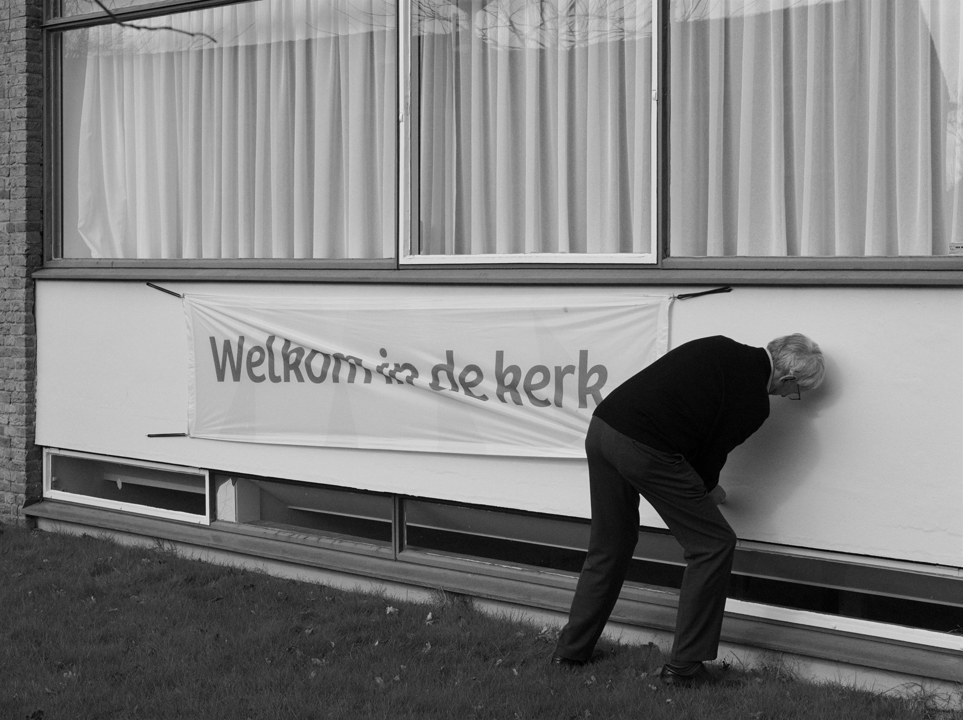 Bent man beside a Welkom in de kerk banner.
