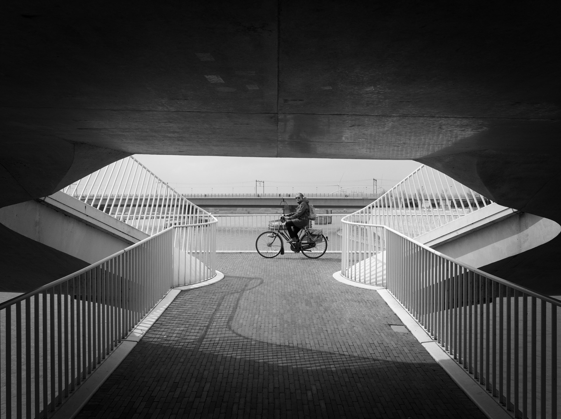 Cyclist beneath a symmetrical viaduct.
