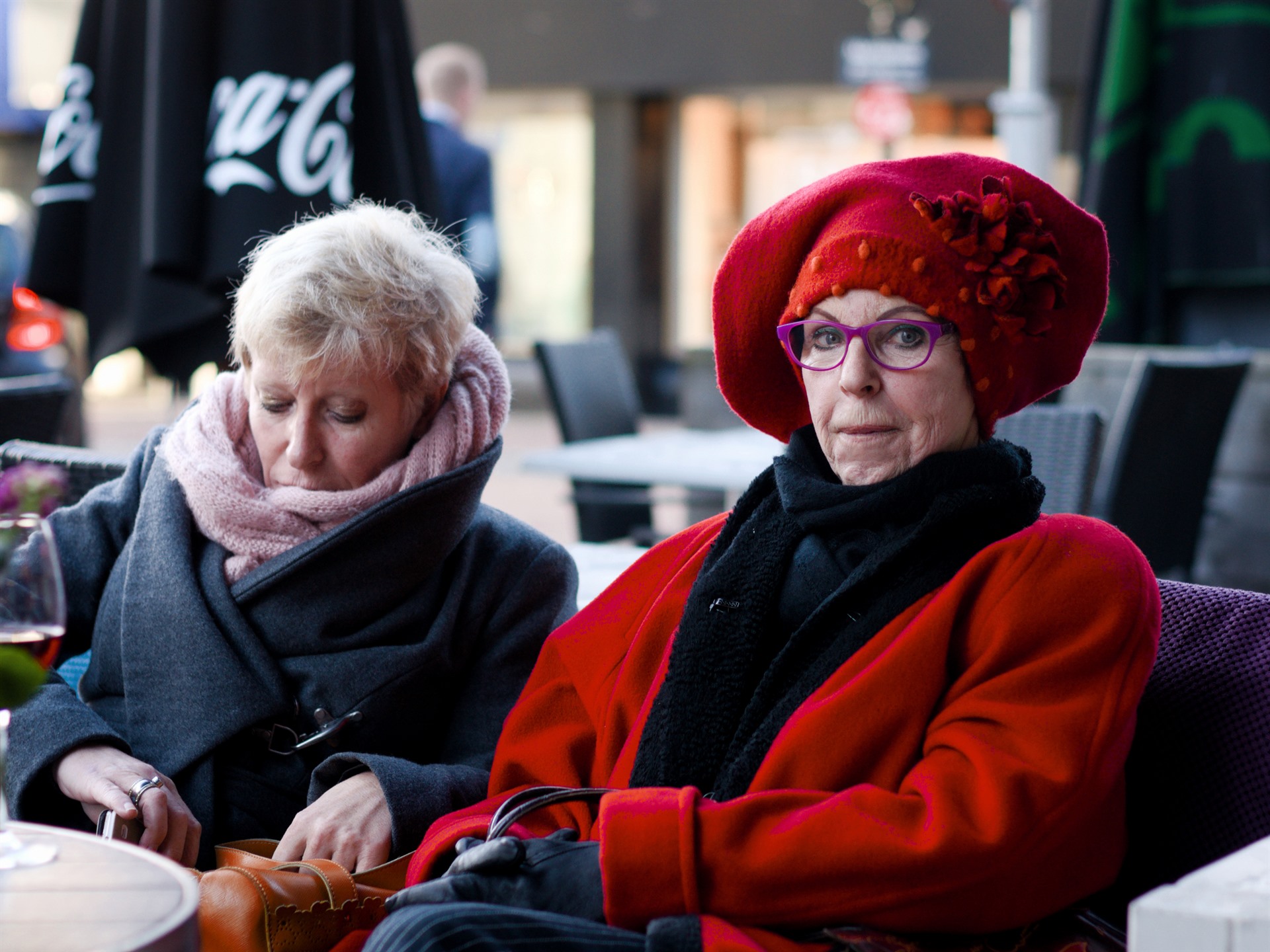 Two older women, one in a red hat.