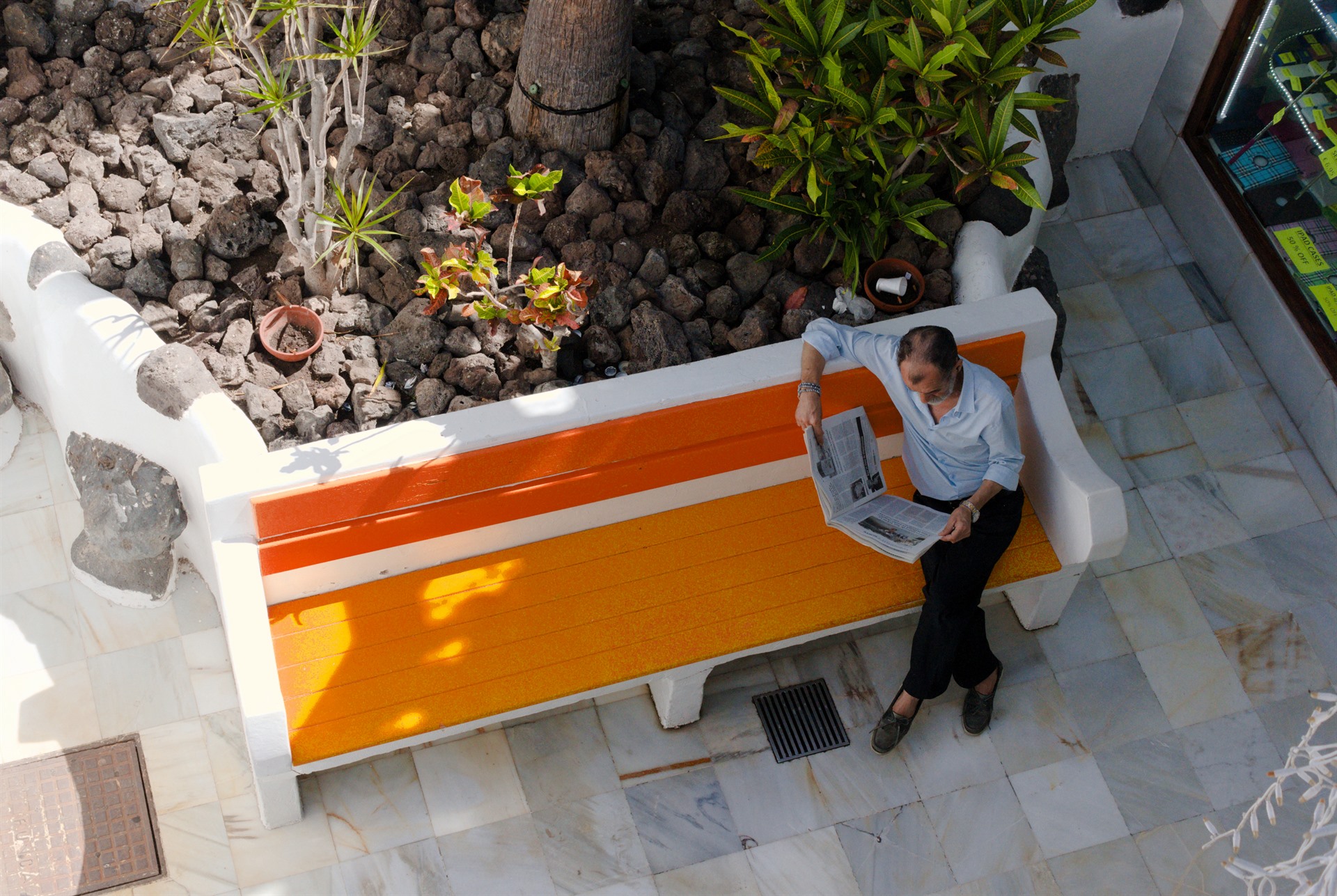 Person beside an orange bench seen from above.