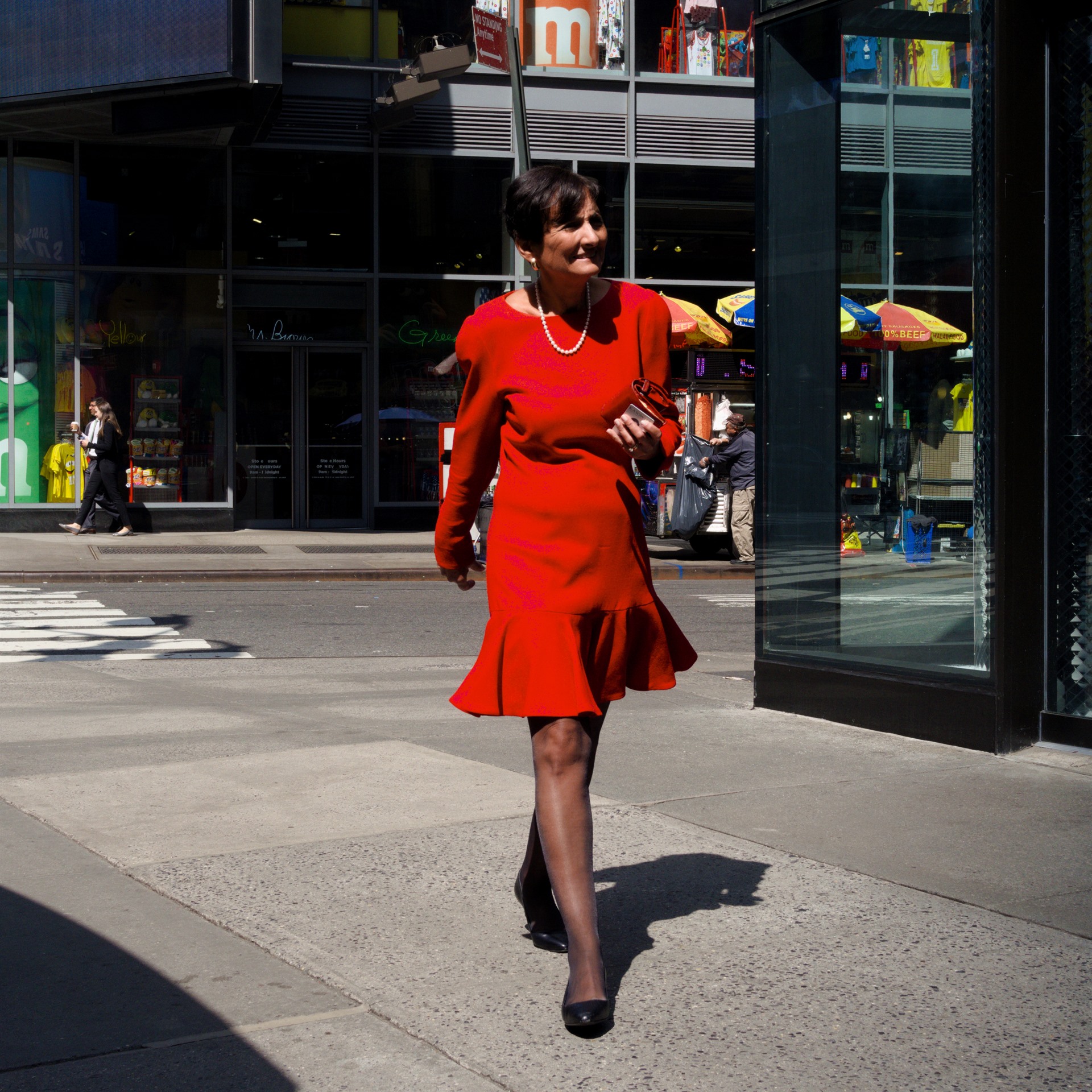 Woman in a red dress crossing a street.