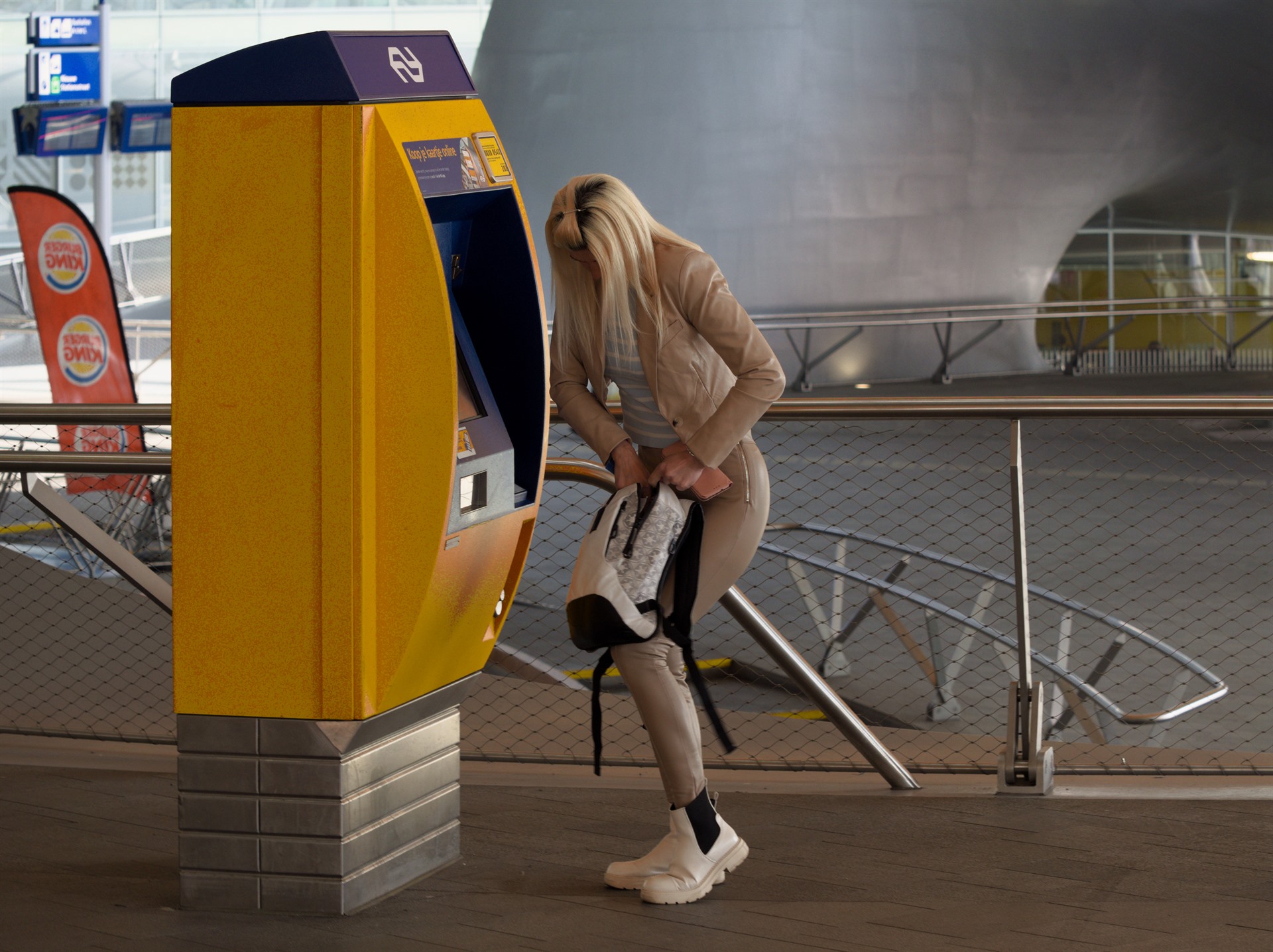 Woman beside a yellow NS ticket machine.