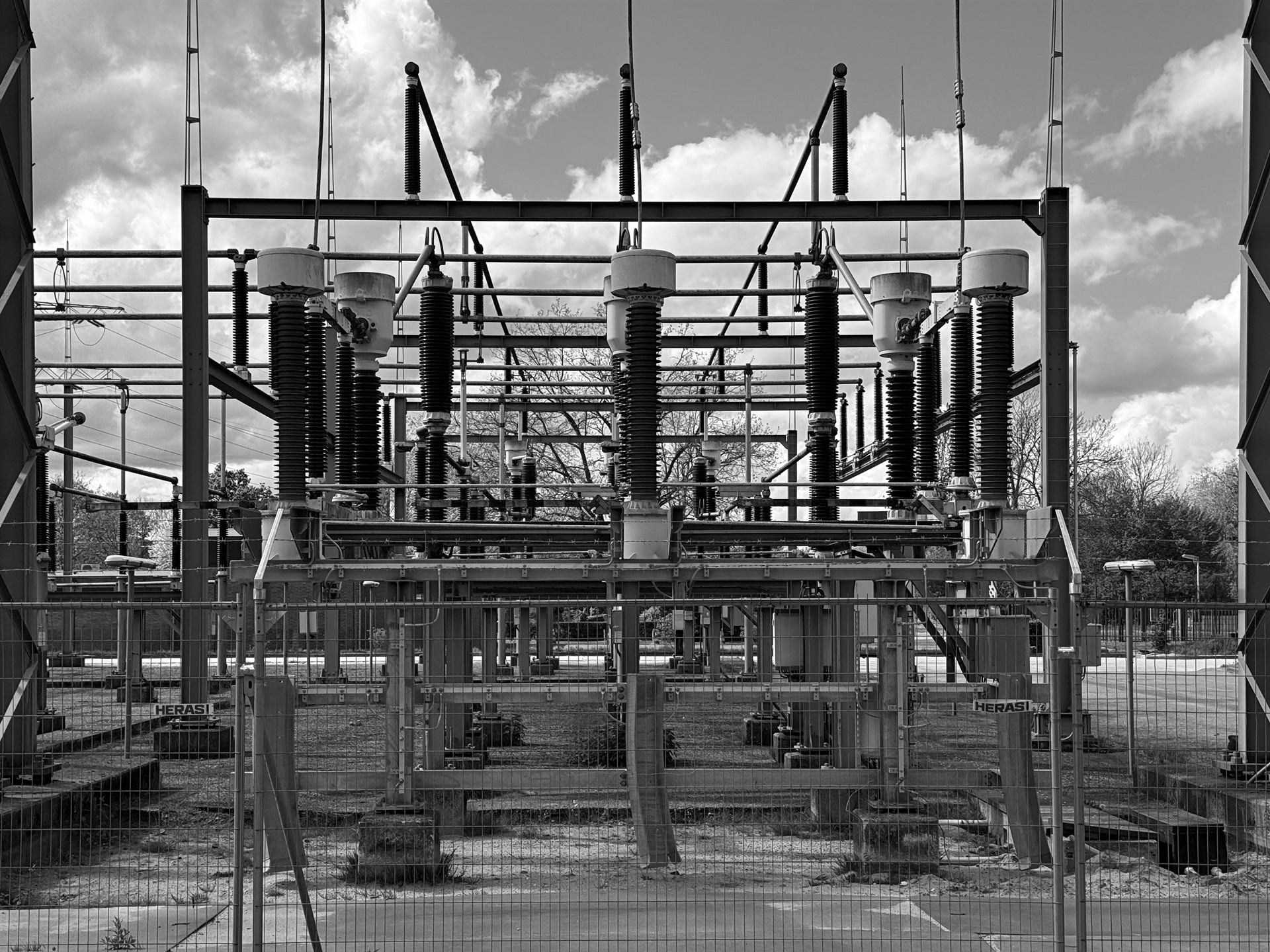 Electrical substation with rows of insulators, cables and metal framework.