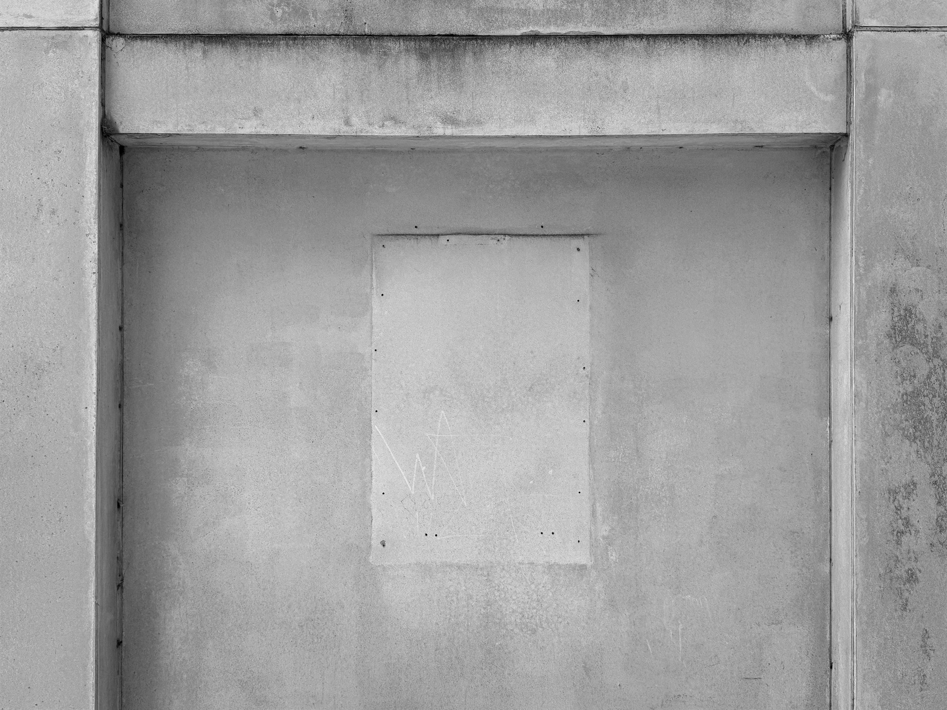 Blank rectangular panel set into a stained concrete wall.