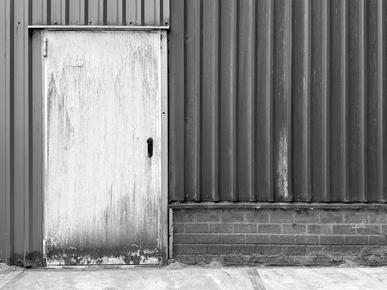 Weather-stained metal door set into a corrugated industrial wall.