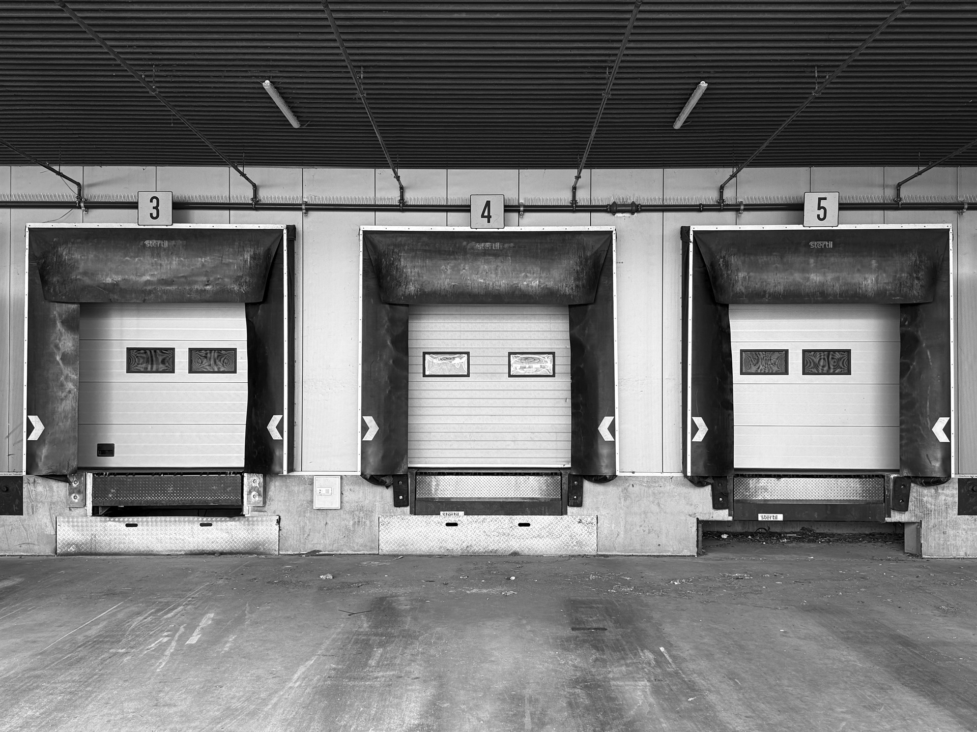 Three numbered loading-bay doors beneath a deep industrial canopy.